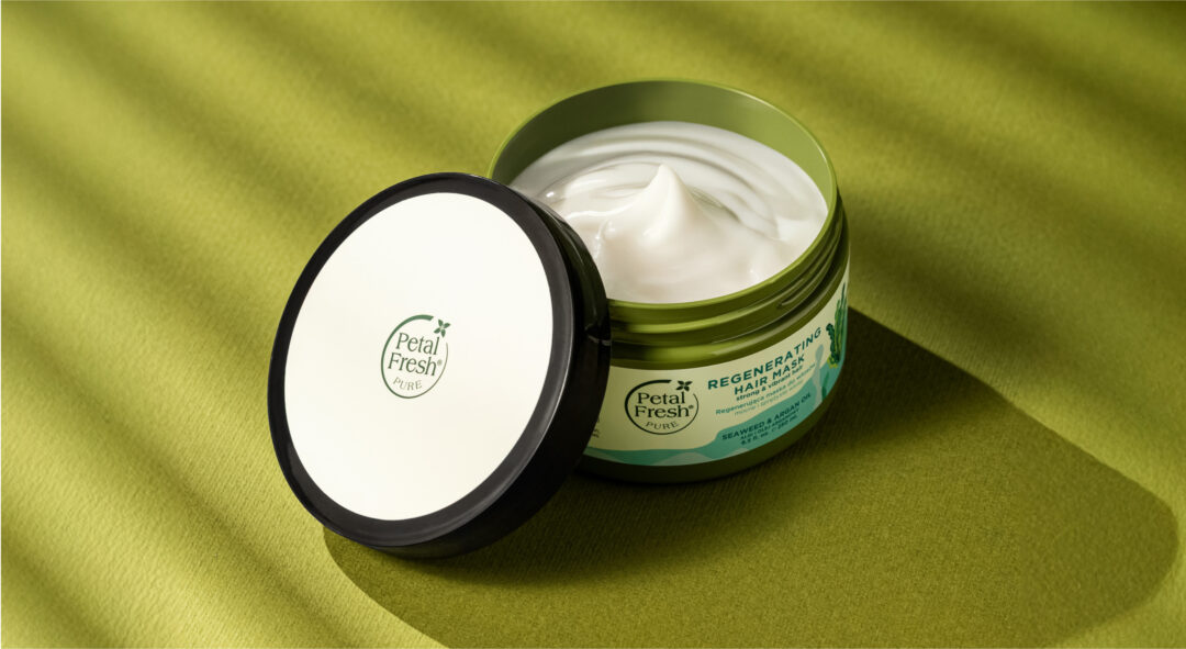 Otwarty słoik z maską do włosów Petal Fresh Pure Regenerating Hair Mask z ekstraktem z alg i olejem arganowym, ukazujący kremową konsystencję, na zielonym tle.
